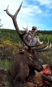 Three Peak Outfitters successful elk hunt on hill hunter lifting up elk head alberta